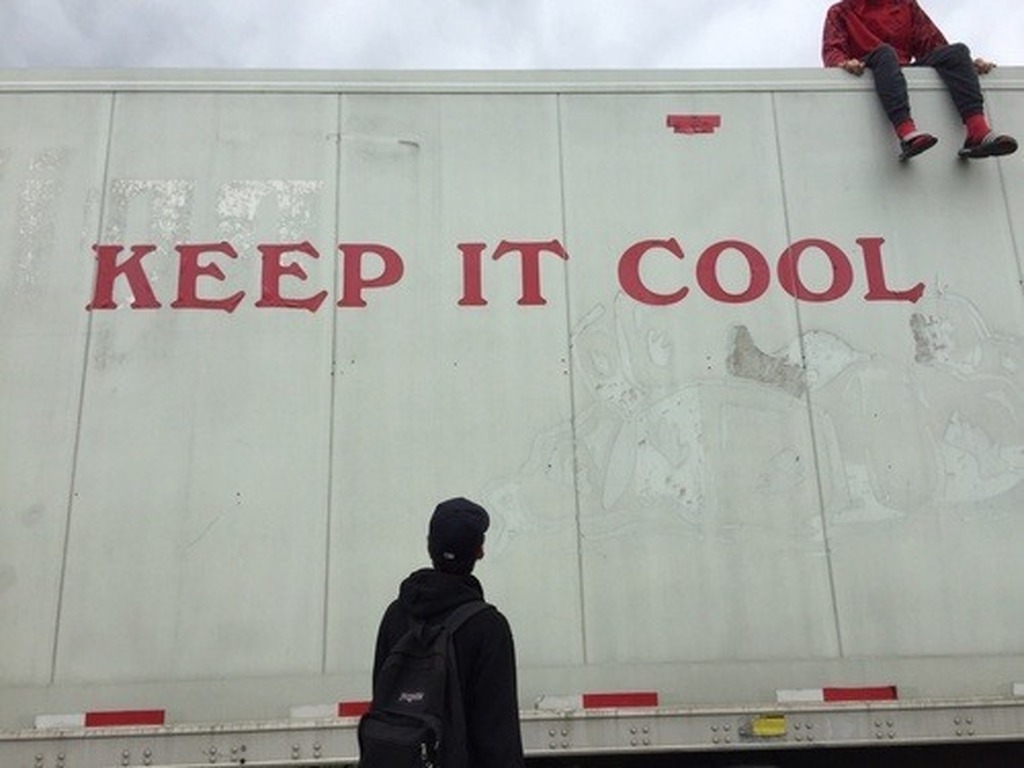 AI caption: two men standing on the top of a truck with the words keep it cool, graffiti