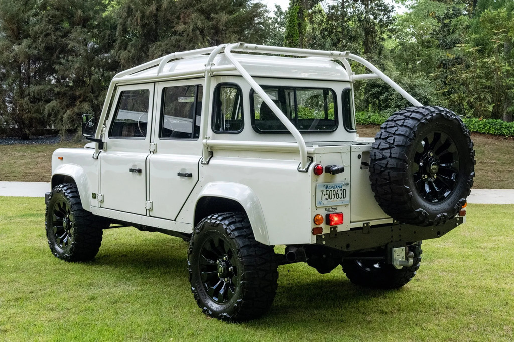 AI caption: a white land rover defender parked in the grass, a white vehicle