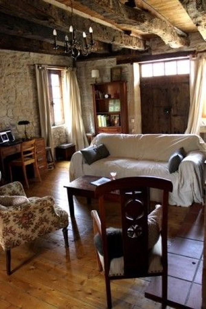 AI caption: a living room with stone walls and wooden beams, rustic
