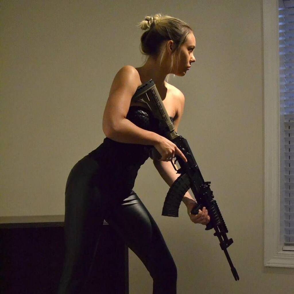 AI caption: a woman in black leather pants holding a gun, black and white