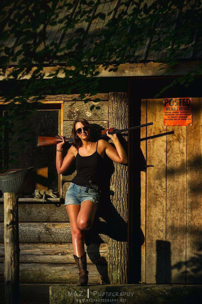 AI caption: a woman with a rifle leaning against a log cabin, rustic