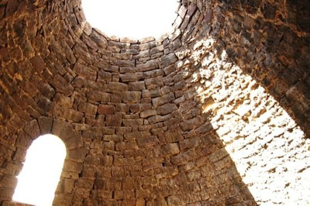 AI caption: a stone tower with a circular opening in it, adobe