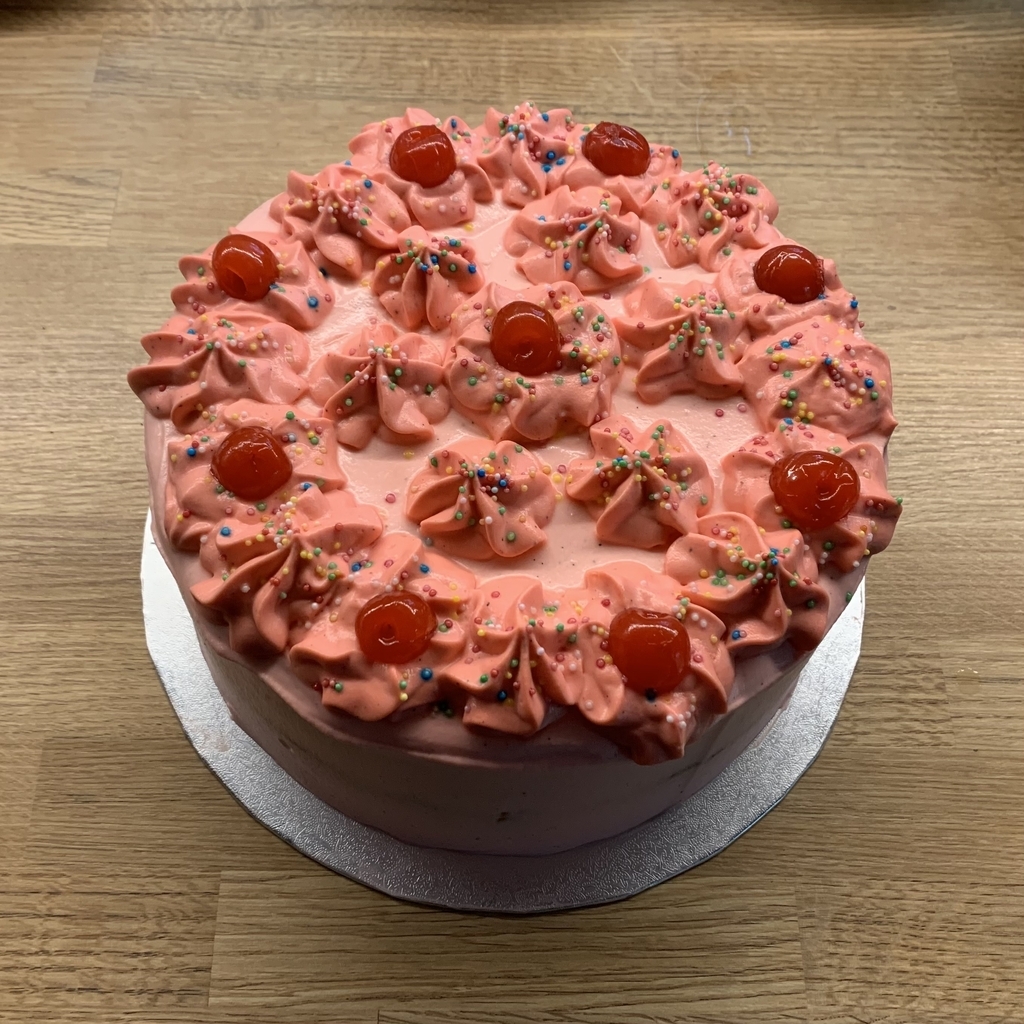 AI caption: a pink cake with icing and cherries on top, a cake