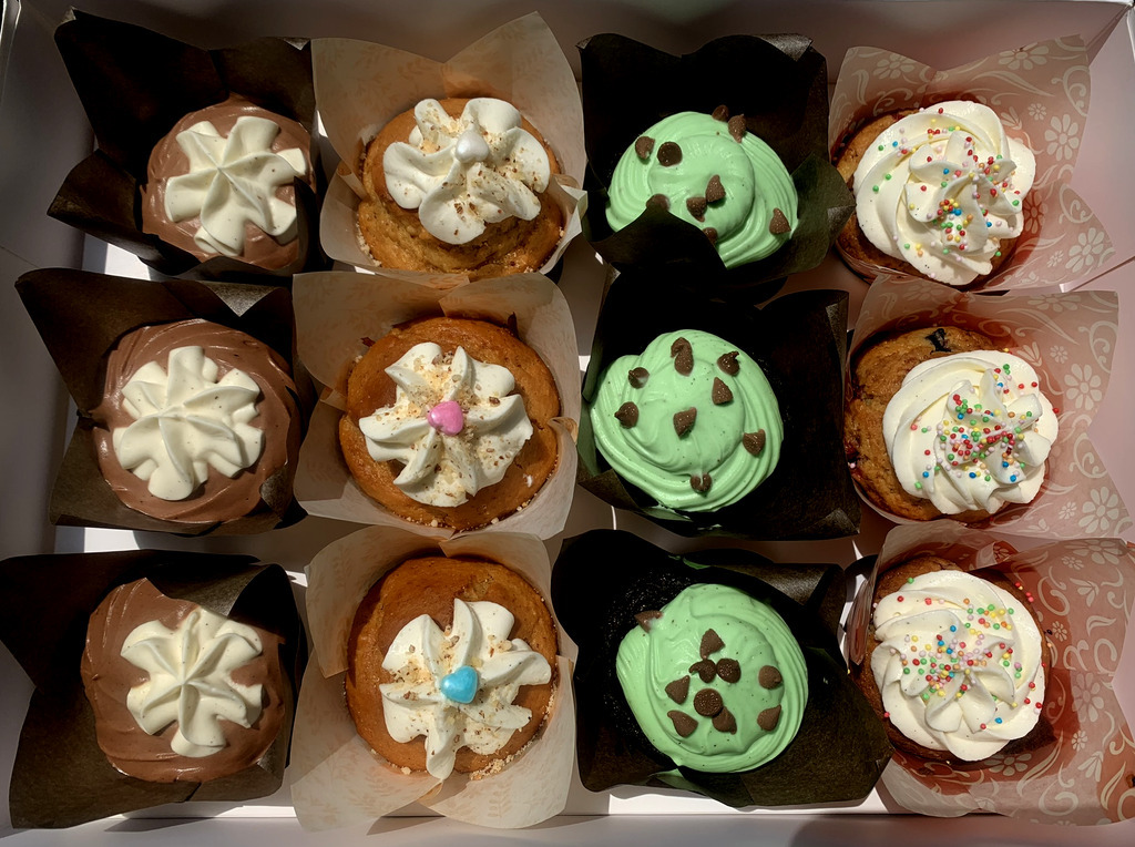 AI caption: a box of cupcakes with frosting and sprinkles, a black and white image